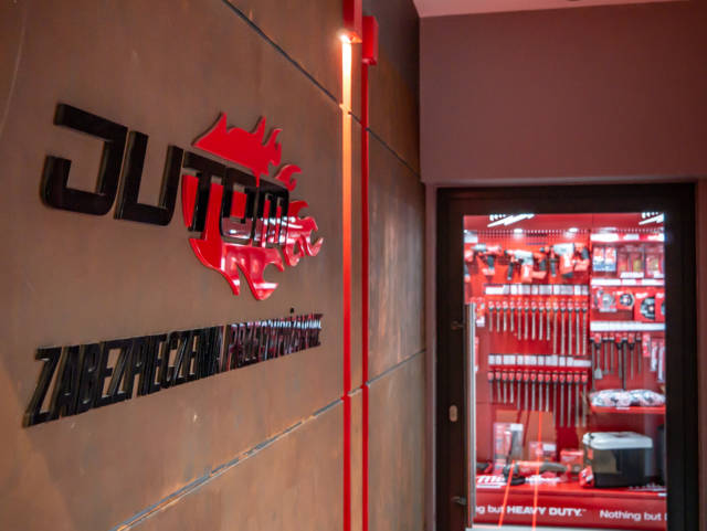Logo firmy Jutom umieszczone na ścianie przed szklanymi drzwiami.